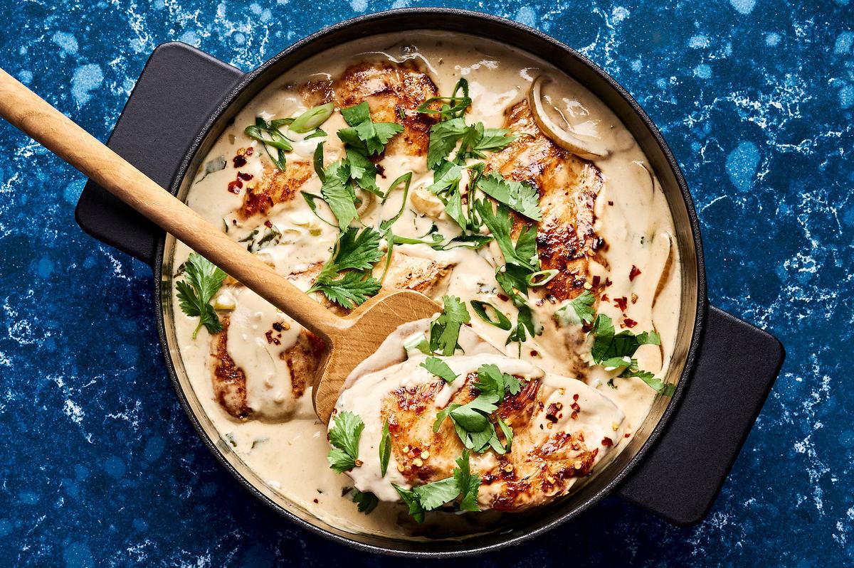 creamy coconut lime chicken in a skillet topped with cilantro, green onions and red pepper flakes