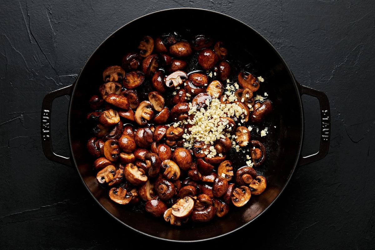 mushrooms and garlic being cooked in butter in a skillet